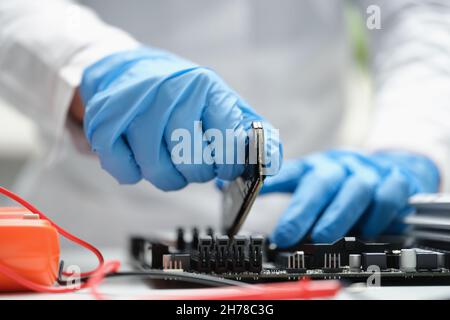 Ein Mann in der Produktion fügt einen Mikrokreis in ein Gerät ein Stockfoto