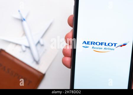 Aeroflot Russian Airlines App auf einem Smartphone-Bildschirm in mans Hand. Ein Spielzeugflugzeug, Reisepass und Tickets stehen auf dem Tisch. November 2021, San Francisco, USA Stockfoto