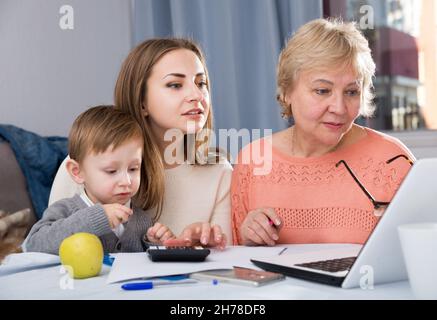 Eine ältere Frau beherrscht mit ihrer Tochter und ihrem Enkel die Technik in der Nähe eines Laptops Stockfoto