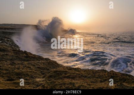 Lange Exposition von den Wellen in den Strand von Chabahar bei Sonnenuntergang in baluchistan, iran. Wellen schlagen die Felsen über oman Meer. Strand mit c Stockfoto