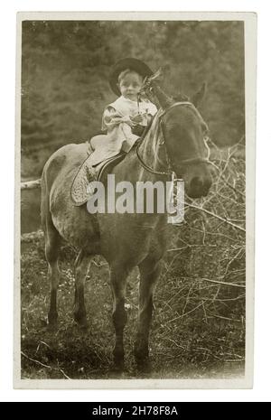 Postkarte des frühen 20. Jahrhunderts, auf der ein Kind auf einem Pferd sitzt, dessen Schwester die Zügel hält, Llandygwydd, Cardiganshire, Wales, Großbritannien, um 1909.