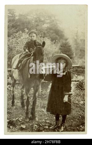 Originalpostkarte aus dem frühen 20. Jahrhundert mit einem kleinen Jungen, der auf einem Pferd sitzt, dessen Schwester die Zügel in der Hand hält, Llandygwydd, Cardiganshire, Wales, Großbritannien, um 1909