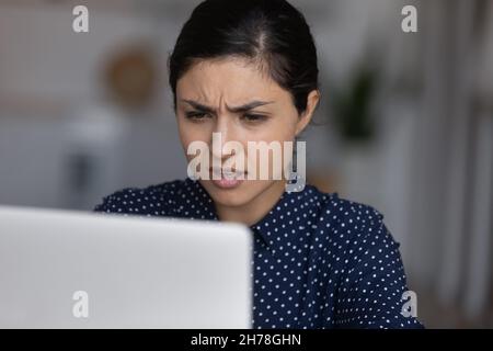 Unglücklich nervös junge indische ethnische Zugehörigkeit Frau Blick auf Laptop-Bildschirm. Stockfoto