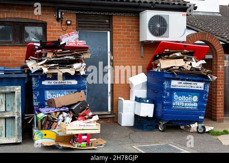 Woodbridge Suffolk UK July 07 2021: Überfließende gewerbliche Abfalleimer voller Kartonrecycling sitzen hinter einem Geschäft, das nicht gesammelt wurde Stockfoto