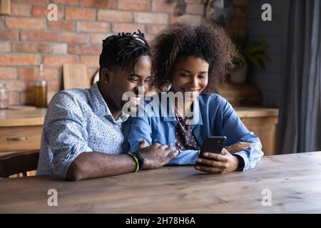 Glückliches junges afroamerikanisches Paar mit Handy. Stockfoto