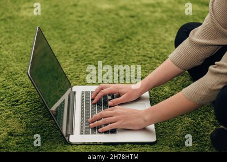 Menschliche Hände über Laptop auf Green Backgroung gelegt Stockfoto