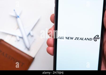 Air New Zealand Airline-App auf einem Smartphone-Bildschirm in mans-Hand. Ein Spielzeugflugzeug, Reisepass und Tickets stehen auf dem Tisch. November 2021, San Francisco, USA Stockfoto