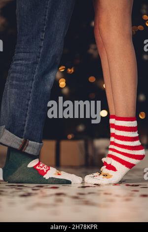 Paar, das in warmen Socken in der Nähe des Weihnachtsbaums steht Stockfoto