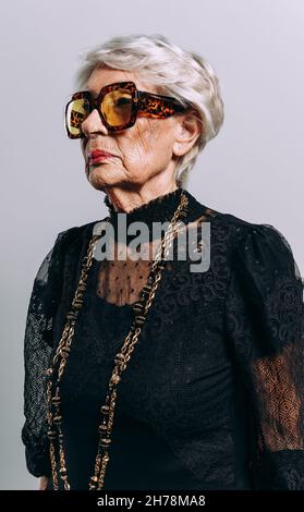 Bild einer schönen und eleganten alten Influencer-Frau. Coole Großmutter posiert im Studio und trägt modische Kleidung Stockfoto
