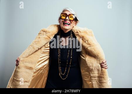 Bild einer schönen und eleganten alten Influencer-Frau. Coole Großmutter posiert im Studio und trägt modische Kleidung Stockfoto