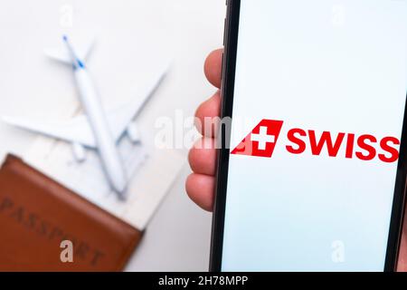 Swiss Airline Anwendung auf dem Bildschirm des Mobiltelefons in mans Hand. Pass, Boarding Bass sind neben einem weißen Flugzeug auf dem Hintergrund. November 2021, San Francisco, USA Stockfoto