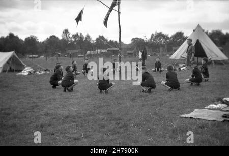 1938, historisch, Kub Scout Camp, The Grand Howl, Felbridge, Surrey, England, Großbritannien. Draußen auf einem Feld kniet sich eine Gruppe von Pfadfindern im Kreis mit ihrem Pfadfinder-Meister in einer Zeremonie nieder, die angeblich von den Wolfspackversammlungen im Dschungelbuch inspiriert wurde, einem berühmten Roman von Rudyard Kipling, Wo die Tiere beginnen, ihren Anführer Akela zu umkreisen und zu heulen. Das Grand Howl versammelt alle und hilft ihnen, sich zu konzentrieren. Robert Baden-Powel, der Gründer der Pfadfinder, hat 1916 ein Programm für Jungen im Alter von 8-10 Jahren eingerichtet und sie als „Wolf Cubs“ bezeichnet. Stockfoto