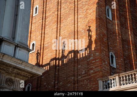 Schatten der Dachskulpturen eines Palastes am Canpanile des Markusplatzes, Venedig, Italien Stockfoto