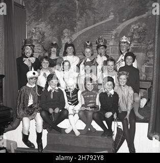 1965, historisch, sitzt zusammen auf einer kleinen Bühne, großes Lächeln von einer Gruppe von Kindern aus einem Jugendzentrum in ihren Kostümen für das Stück, Alice in Wonderland, Fife, Schottland, Großbritannien. Stockfoto