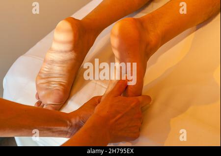 Fußsohlenmassage, masseuse Hände massieren Männerfuß Stockfoto