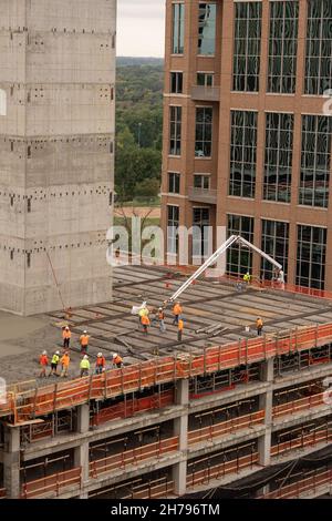 Eine Baumannschaft gießt Beton auf eine Baustelle im Geschäftsviertel. Das Gebäude befindet sich im Bau in Clayton, MO, einem Vorort von St. Louis, MO, USA. Stockfoto