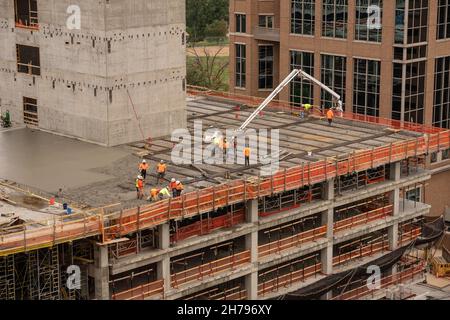 Eine Baumannschaft gießt Beton auf eine Baustelle im Geschäftsviertel. Das Gebäude befindet sich im Bau in Clayton, MO, einem Vorort von St. Louis, MO, USA. Stockfoto