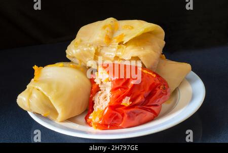 Pfeffer und gefüllte Kohlrollen auf einem Teller. Essen auf schwarzem Hintergrund Stockfoto