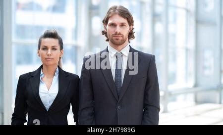 Porträt von zwei Geschäftsleuten, Mann und Frau, die in der Lobby des modernen Gebäudes stehen Stockfoto