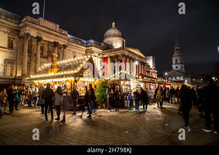 LONDON, Großbritannien - 20th. NOV 2021: Weihnachtsmärkte und Stände vor der National Gallery am Trafalgar Square. Viele Menschen sind zu sehen. Stockfoto
