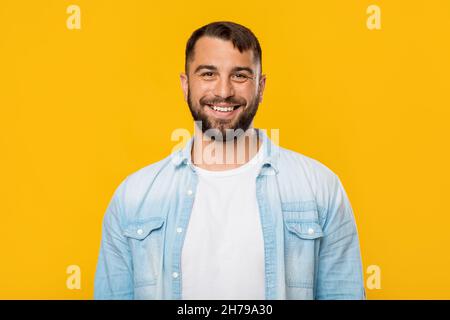 Lächelnder, glücklicher, reifer europäischer Mann, der die Kamera anschaut, isoliert auf gelbem Hintergrund, freier Raum Stockfoto