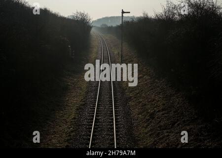 Eine eingleisige Eisenbahnlinie, die ein Signal passiert und durch die Landschaft in die Ferne verschwindet. Stockfoto