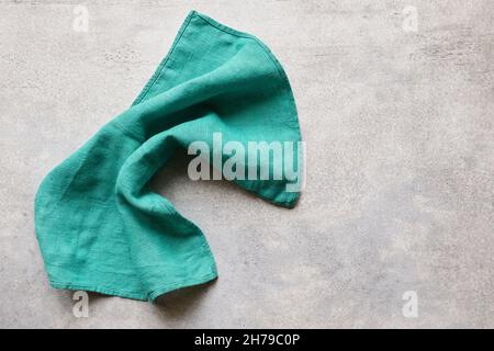 Grüne gefaltete Leinenserviette auf grauem Betontisch mit Kopierfläche, Draufsicht Stockfoto