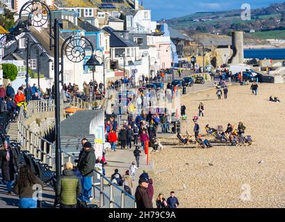 Lyme Regis, Dorset, Großbritannien. 21st. November 2021. Wetter in Großbritannien: Besucher und Einheimische wärmen sich an einem sonnigen und hellen, aber kühlen Nachmittag auf einen Spaziergang entlang der Strandpromenade des malerischen Badeortes Lyme Regis. Der Kredit: Celia McMahon/Alamy Live Nachrichten Stockfoto