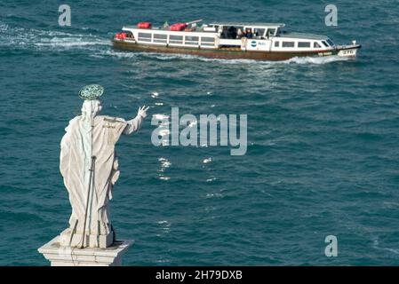 Skulptur von Jesus auf dem Dach der Basilica di San Giorgio Maggiore mit Blick auf den Kanal und einem vorbeifahrenden Vaporetto, Venedig, Italien Stockfoto