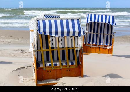 An einem Sandstrand an der Ostseeküste in Kolobrzeg, Polen, stehen Liegestühle mit kleinen Dächern, die vor der Sonne schützen. Stockfoto