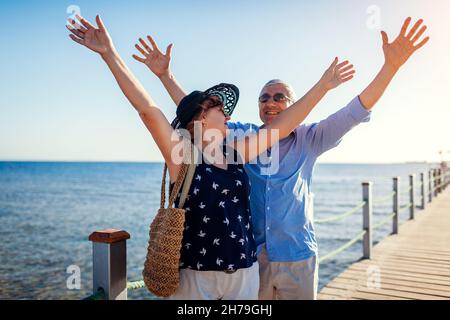 Ein älteres Familienpaar, das am Pier am Roten Meer die Arme hochhebt. Glückliche Rentner, die Urlaub in Sharm el Sheikh in Ägypten feiern. Stockfoto