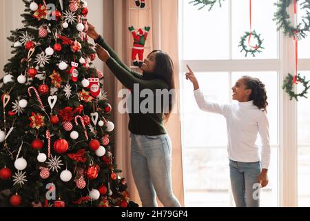 Glückliche schwarze Frau und Mädchen Dekoration Weihnachtsbaum Stockfoto