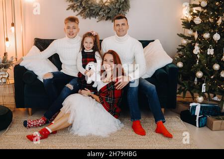 Nahaufnahme einer glücklichen Familie, die auf einem Sofa in der Nähe eines Weihnachtsbaums sitzt und einen Feiertag feiert. Stockfoto