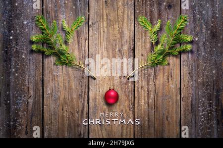 Weihnachtskonzept - Rentier Aus Tannenzweigen Und Rotkugel Auf Holzplanke Stockfoto