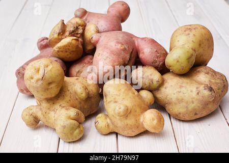 Hässliches organisches abnormes Gemüse, seltsame Kartoffeln. Platz für Text. Das Konzept von Bio-Gemüse. Hintergrund aus weißem Holz Stockfoto