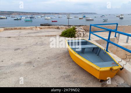 Kleines gelbes Boot liegt auf dem Boden im Hafen von Mellieha, Malta Stockfoto