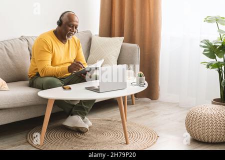 Senior African American Man Using Laptop Taking Notes At Home Stockfoto