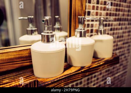Flaschenspender mit Shampoos und Seife und anderen Hygieneflüssigkeiten auf dem Regal im Badezimmer Stockfoto
