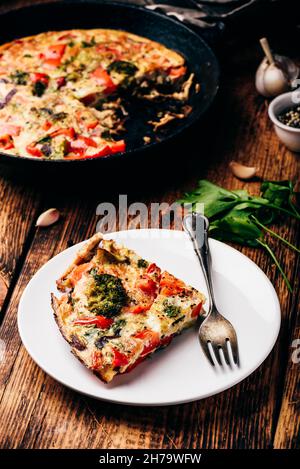 Gemüse frittata mit Brokkoli, rote Paprika und Zwiebel rot auf weiß Platte und in einem Guss Stockfoto