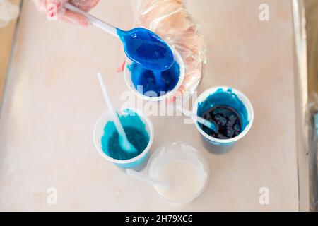 Epoxidharz verschiedene blaue Farbe in Tasse zum Gießen stabilisierendes Holz, abstrakte Kunst. Prozess der Herstellung von Zubehör aus Harz.Mischen bunt von Harz Stockfoto