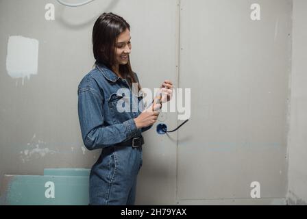 Junge schöne Frau macht Reparaturen in der Wohnung. Das Mädchen macht Reparaturen zu Hause auf ihre eigenen Farben die Wände Stockfoto