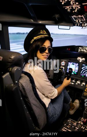 Weibliche Pilotin im Flugzeug-Cockpit. Pilot trägt Sonnenbrille und Hut Stockfoto