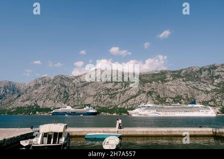 Braut und Bräutigam stehen auf dem Pier vor dem Hintergrund von Kreuzfahrtschiffen und Bergen Stockfoto