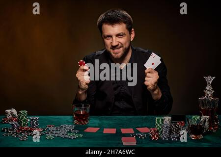 Bärtiger Casino Spieler Mann, der Poker auf dem grünen Tisch spielt Stockfoto