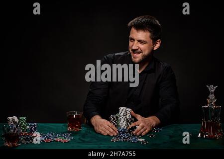Bärtiger Casino Spieler Mann, der Poker auf dem grünen Tisch spielt Stockfoto