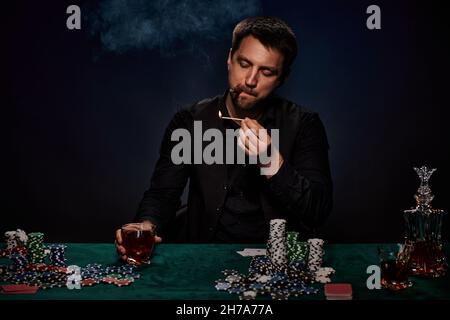 Bärtiger Casino Spieler Mann, der Poker auf dem grünen Tisch spielt Stockfoto