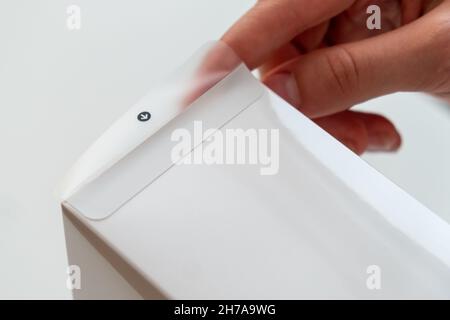 Nahaufnahme des Auspackens einer weißen Schachtel durch weibliche Hände. Ein Geschenkkonzept erhalten. Stockfoto