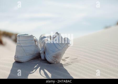 Rückansicht der Knöchelschuhe Paar auf Sand. Selektiver Fokus. Sommerurlaub, Urlaub am Meer Konzept. Stockfoto