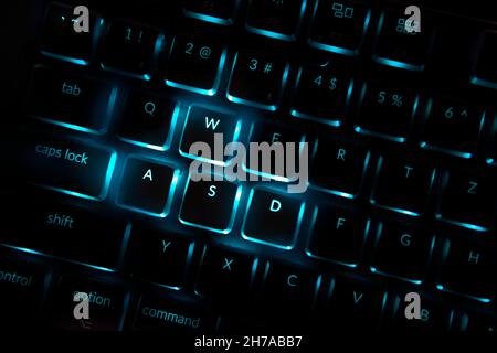 Blaue Computertastatur mit Hintergrundbeleuchtung. Nahaufnahme der hervorgehobenen Standardtasten in Spielen, die mit Bewegungen verbunden sind. Professionelle Computerspiele spielen, Stockfoto