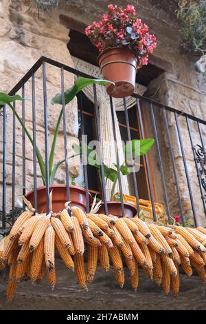 Mais auf der Kohlenpfanne Ernte Trocknung auf dem Balkon eines alten Steinhauses in Horta de Sant Joan in Spanien Stockfoto